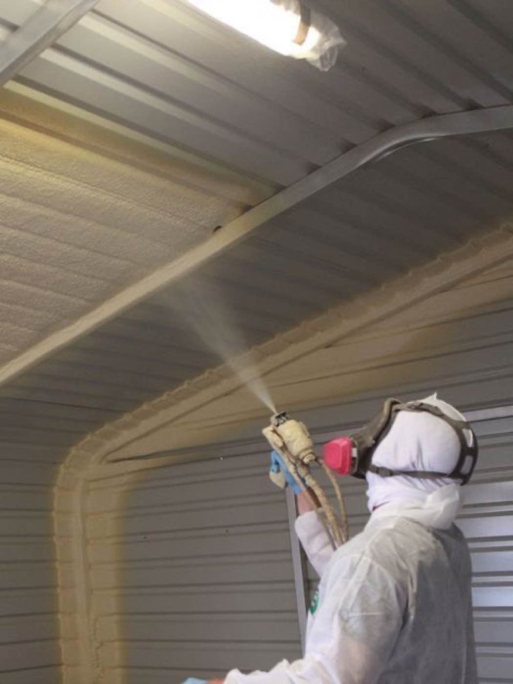 Spray foam being applied to the underside of a metal roof deck