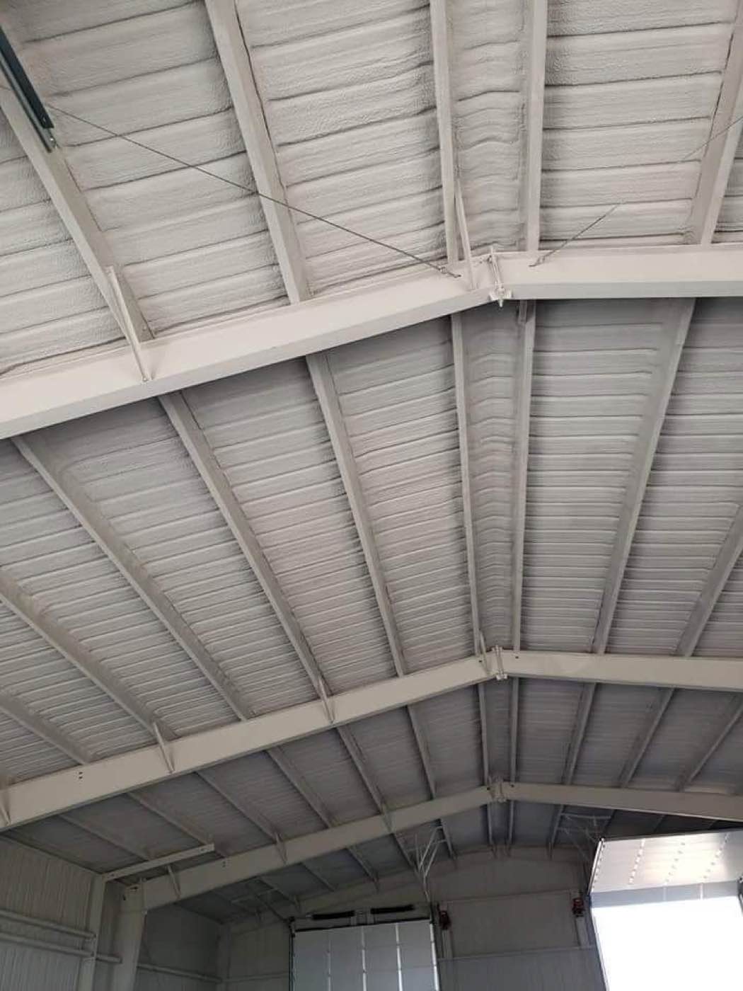 Metal building roof structure insulated with spray foam